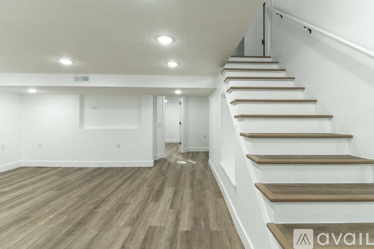A staircase with wooden steps and handrails leads up to a white wall.