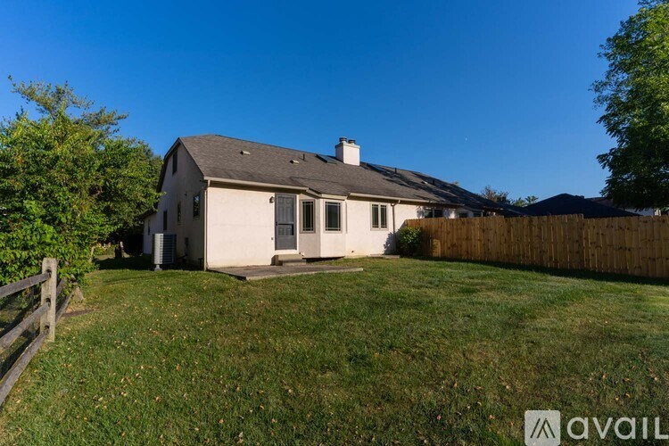 A house with a fence and a tree in front of it.