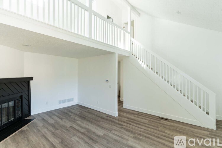A spacious room with a staircase and a fireplace.