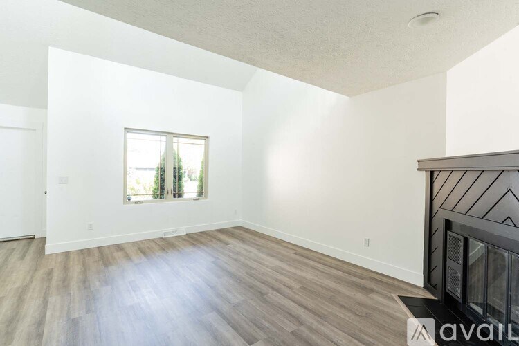 A spacious room with wooden flooring and a large window.