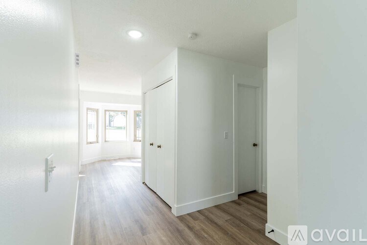 A hallway with white walls and wooden floors.