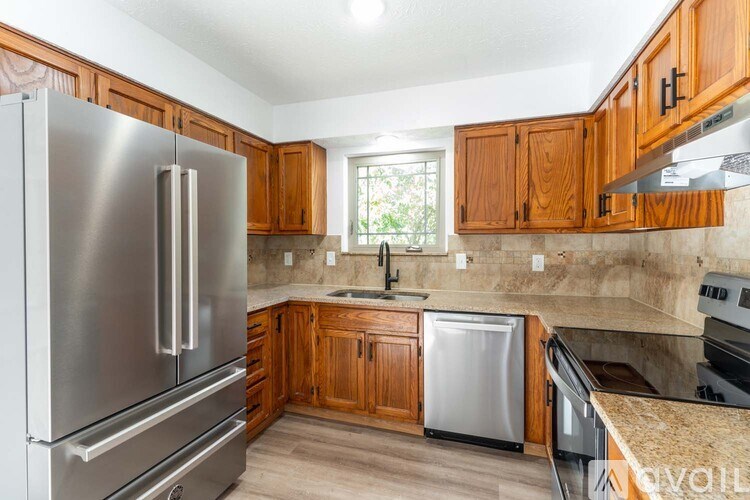 A kitchen with wooden cabinets and a stainless steel refrigerator.