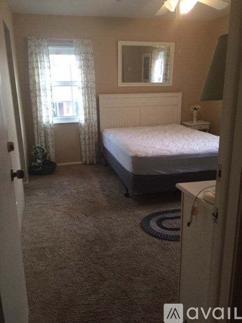 A bedroom with a bed, dresser, and window.