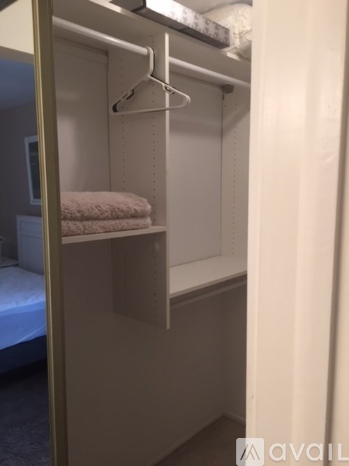 A small white closet with a towel hanging on a hanger.