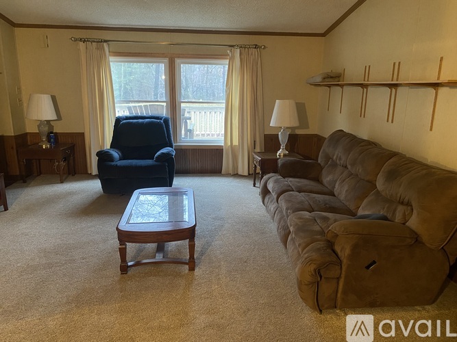 A living room with a blue chair, brown couch, and a coffee table.