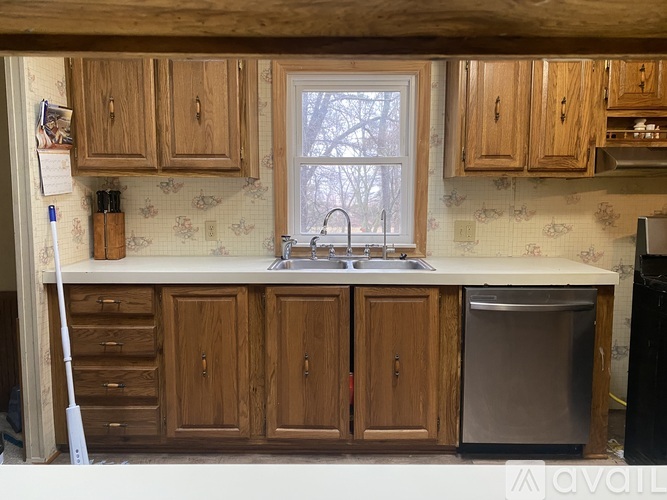 A kitchen with wooden cabinets and a window above the sink.