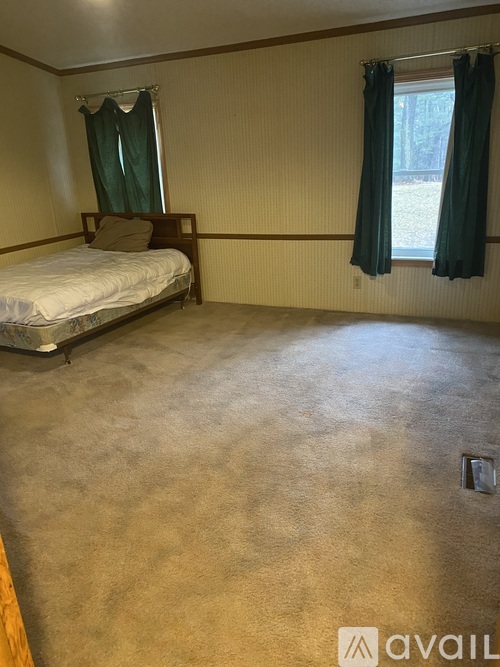 A bedroom with a bed, window, and carpeted floor.