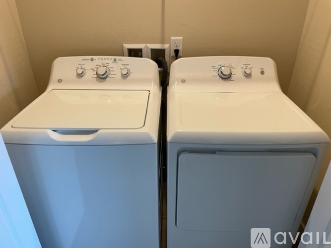 Two white front loading washing machines in a small laundry room.