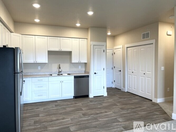 A kitchen with white cabinets and a black refrigerator.