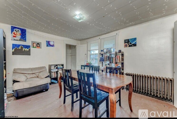 A living room with a sofa, chairs, and pictures on the wall.