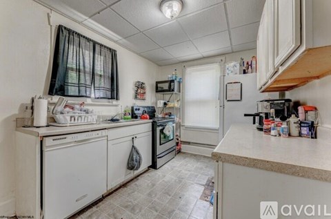 A kitchen with white appliances and a tiled floor.