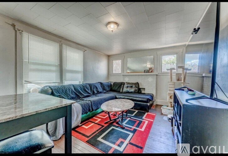 A living room with a couch, a table, and a rug.