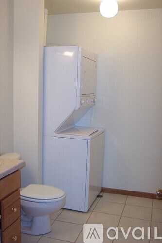 A white fridge in a small bathroom with a toilet.
