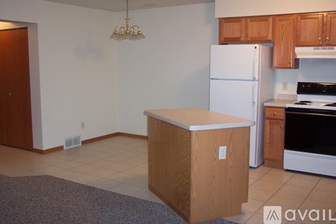 A kitchen with a white refrigerator and a wooden island.