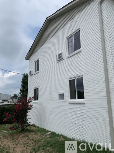 A white house with a window and a bush in front.
