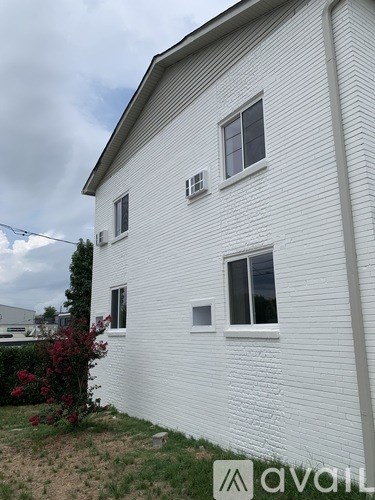 A white house with a window and a bush in front.