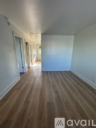 A hallway with wood flooring and white walls.