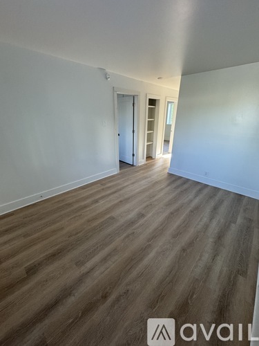 A room with wooden flooring and white walls.