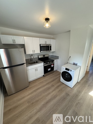 A kitchen with a stainless steel refrigerator and a white washing machine.