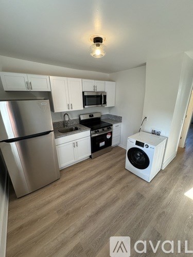 A kitchen with a stainless steel refrigerator and a white washing machine.