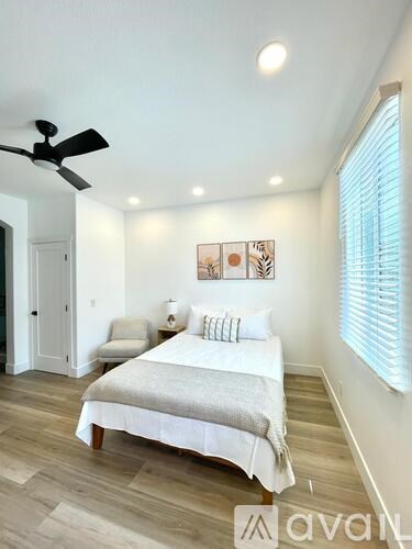 A bedroom with a bed, a chair, and a ceiling fan.
