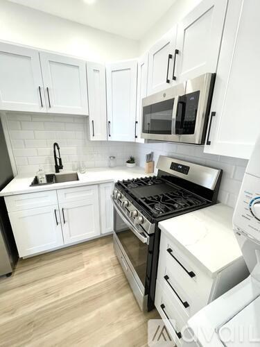 A modern kitchen with white cabinets and appliances.