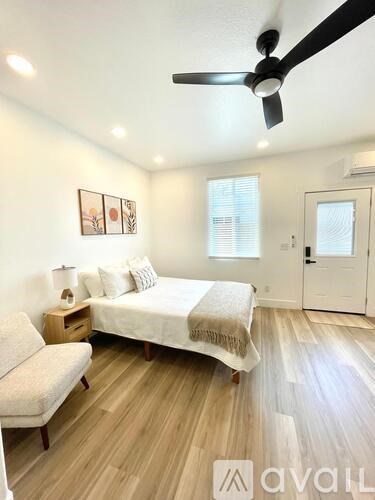 A bedroom with a bed, a couch, and a ceiling fan.