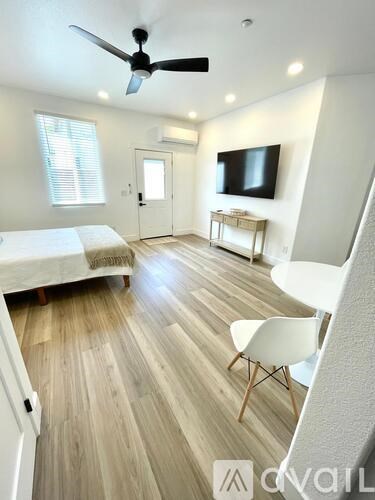 A bedroom with a bed, chair, and tv.