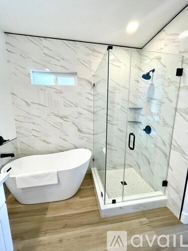 A white bathtub with a glass shower door in a bathroom.