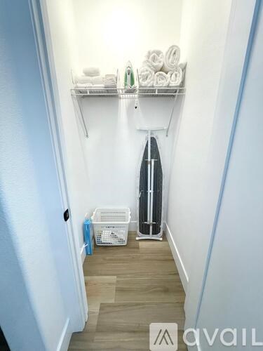 A hallway with a surfboard and a basket on the floor.