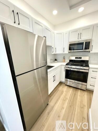 A kitchen with white cabinets and a stainless steel refrigerator.