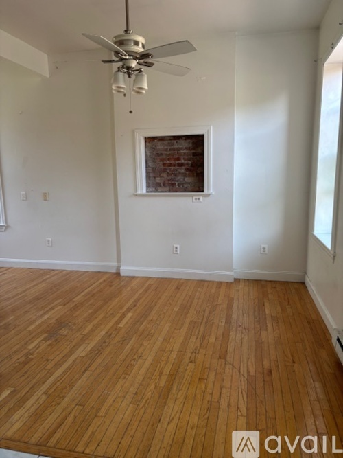A room with wooden flooring and a ceiling fan.
