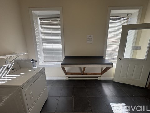 A kitchen with a white sink and black tiles on the floor.