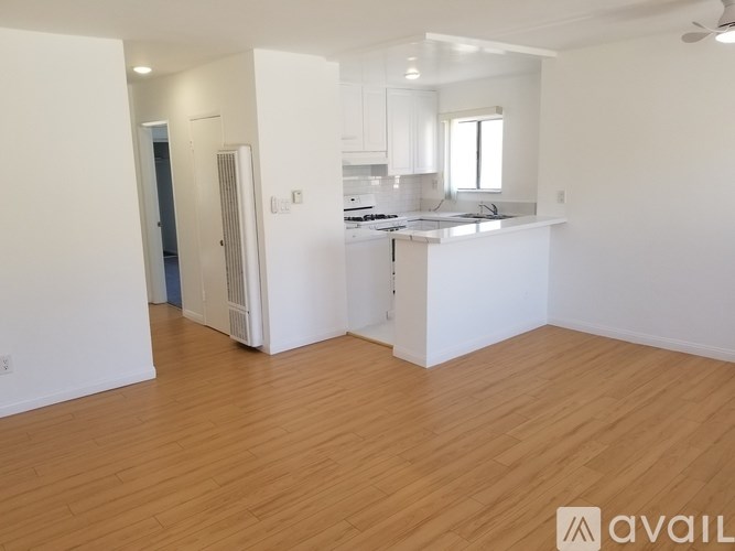 A spacious kitchen and living room with wooden flooring and white walls.