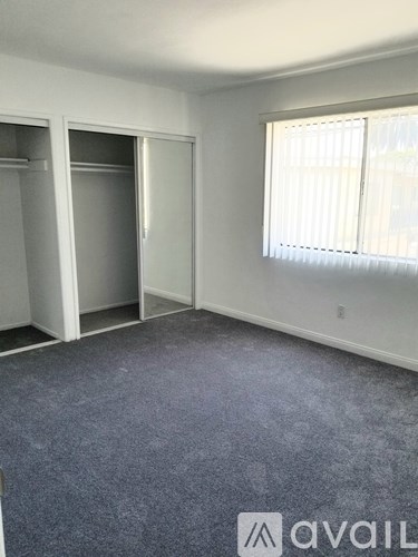 A room with a carpeted floor and two open closets.