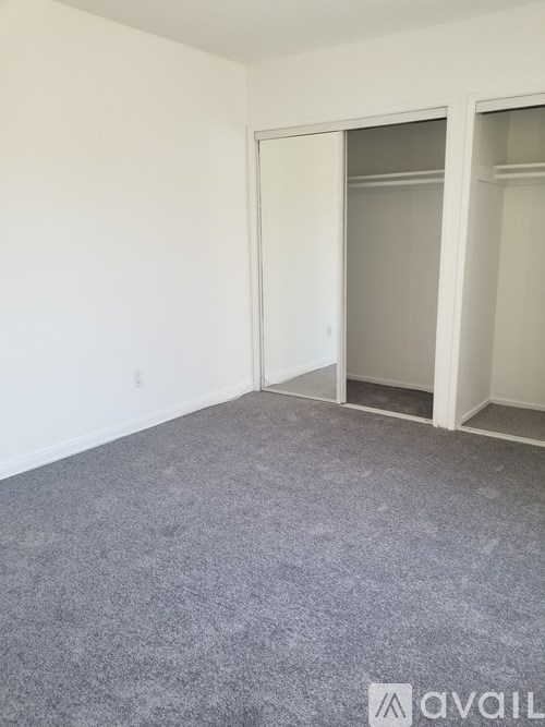 A room with a grey carpet and a white door.
