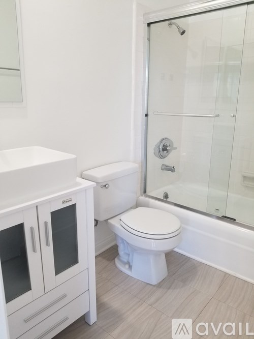 A white toilet sits next to a glass shower stall in a bathroom.