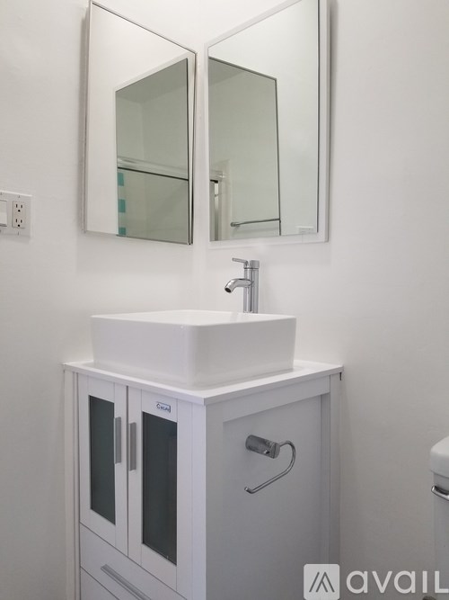 A white sink with a cabinet and a mirror above it.
