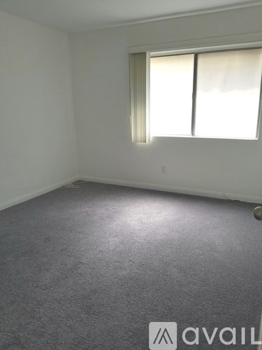 A room with a carpeted floor and a window with blinds.