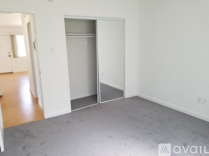 A room with a white wall and a grey carpet.