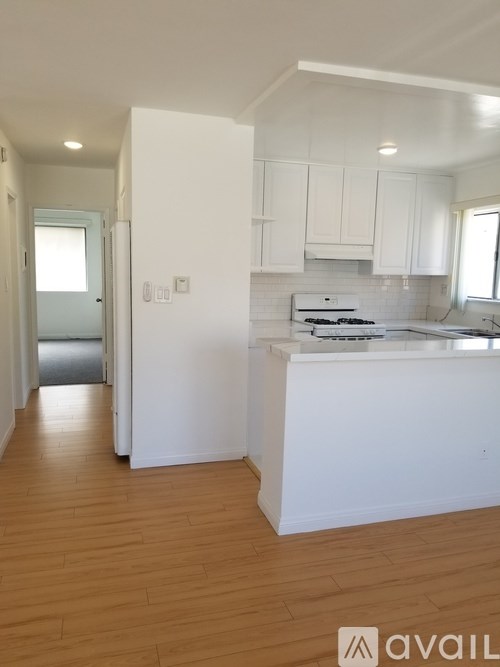 A kitchen with white cabinets and a wooden floor.