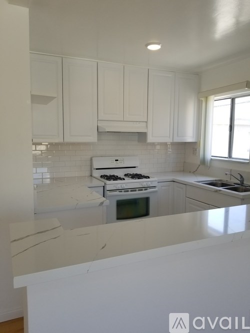 A kitchen with white cabinets and a white stove top oven.
