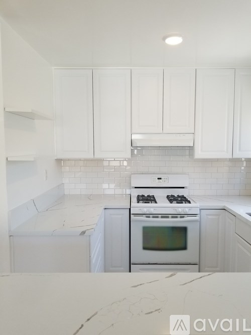 A kitchen with white cabinets and a white stove top oven.