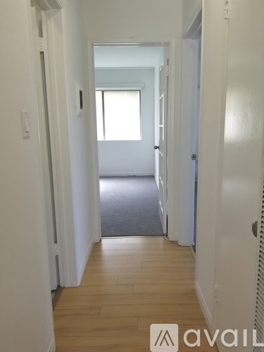 A hallway with wooden floors and white walls.