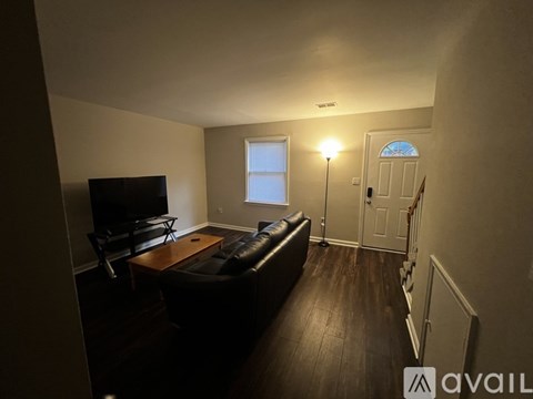 A living room with a brown leather couch and a television.