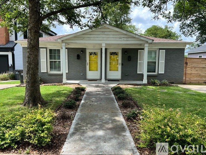 A small house with a yellow door and a grey front yard.