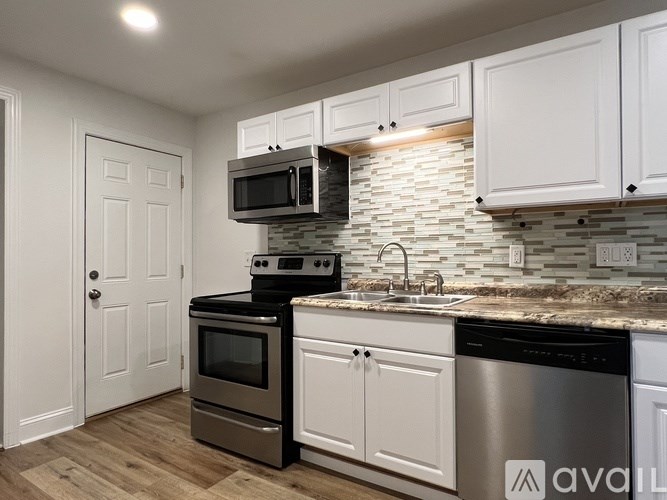 A kitchen with white cabinets and a stone backsplash.
