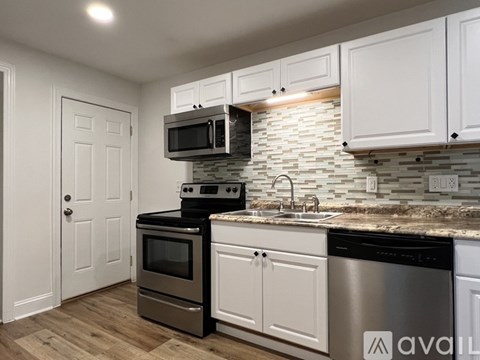 A kitchen with white cabinets and a stone backsplash.