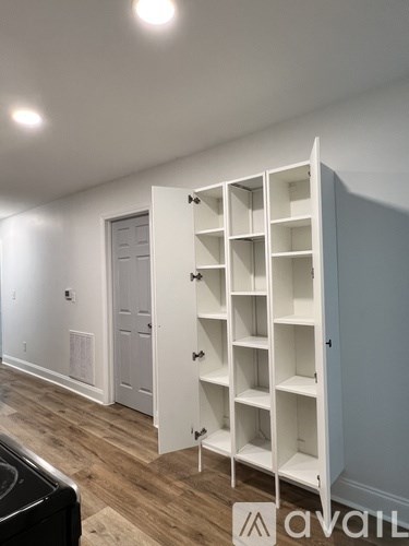 A white shelving unit is open in a room with a black object on the floor.