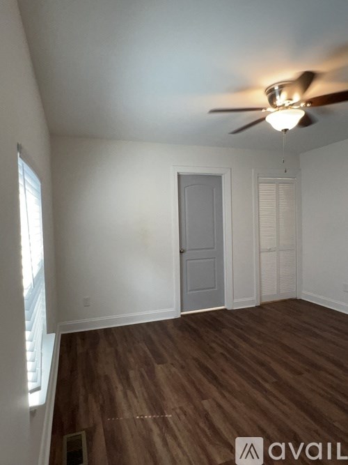 A room with a ceiling fan and wooden flooring.